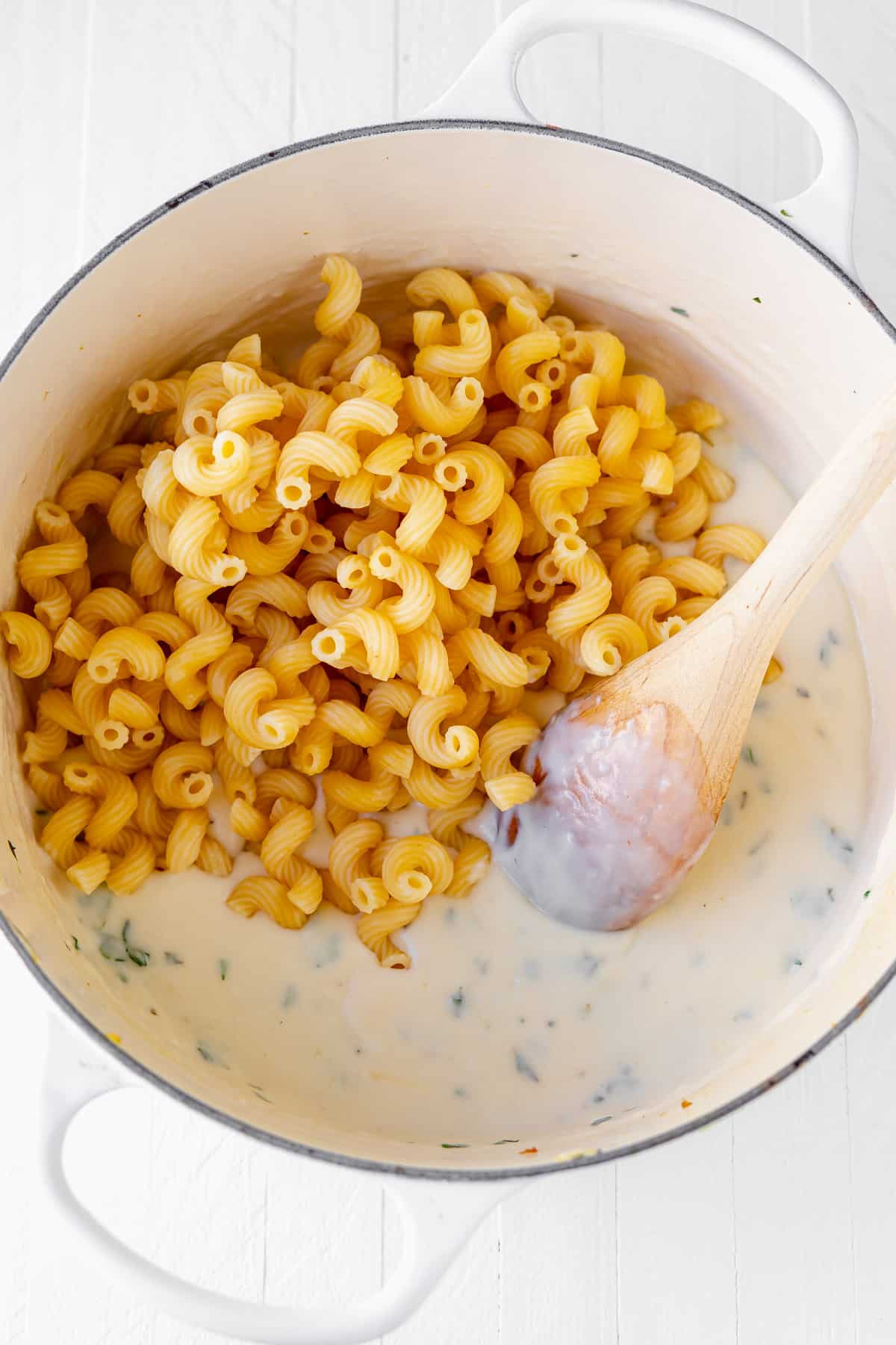 Cavatappi noodles being added to the cheese sauce for tuscan chicken mac and cheese.