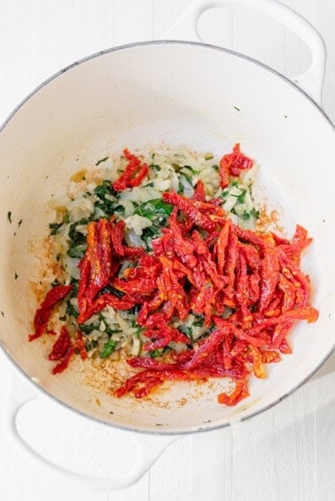Sauteeing ingredients together for Tuscan Chicken Mac and Cheese.