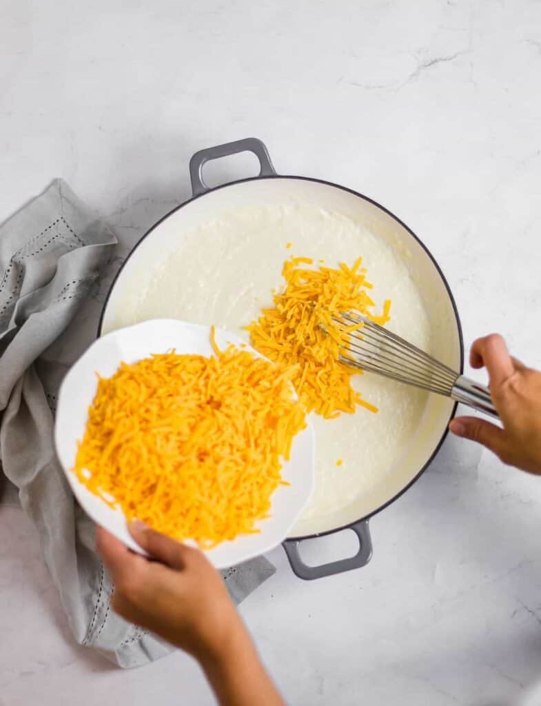 adding shredded cheese to roux to make sauce