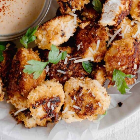 Fried chicken nuggets with dipping sauce served on a plate.