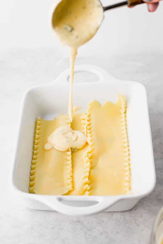 Pouring cheese sauce over pasta noodles. 