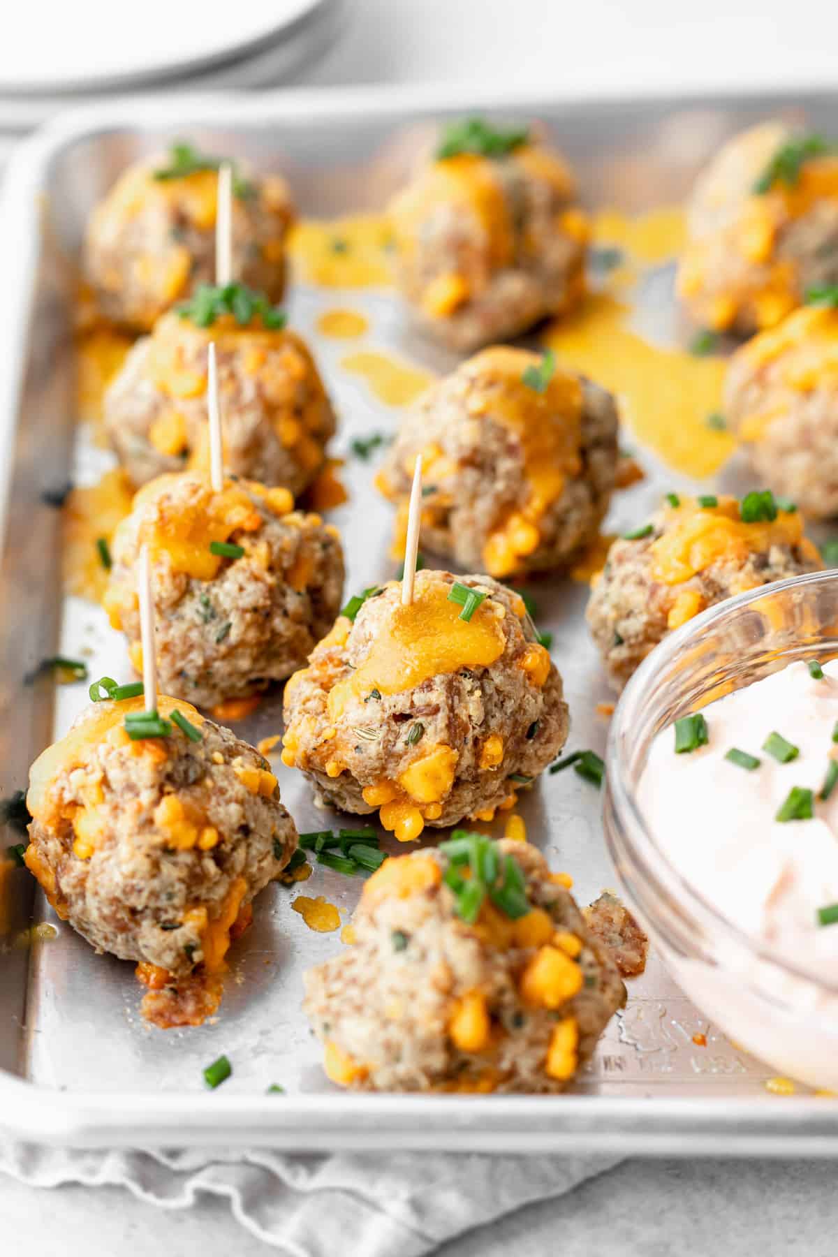 cream cheese sausage balls on a baking tray with toothpicks, ready to be dipped into garlic sauce