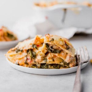 A slice of chicken alfredo lasagna on a plate with a fork.