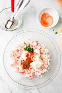 A glass bowl filled with a mixture of salt, pepper and cold crab dip.