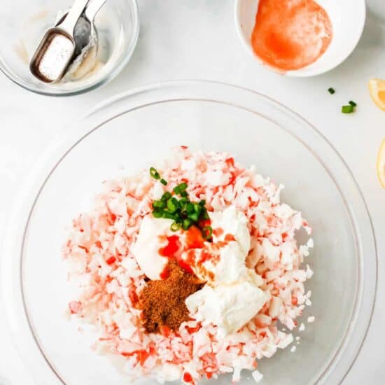 A glass bowl filled with a mixture of salt, pepper and cold crab dip.