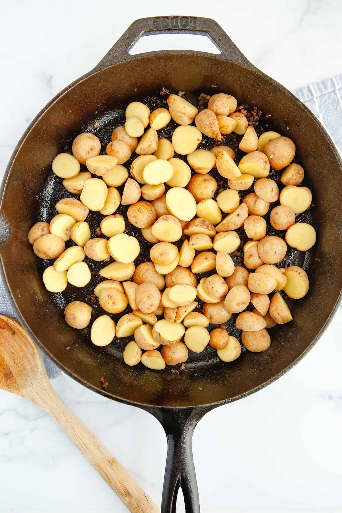 Halved baby potatoes in a cast iron pan. 