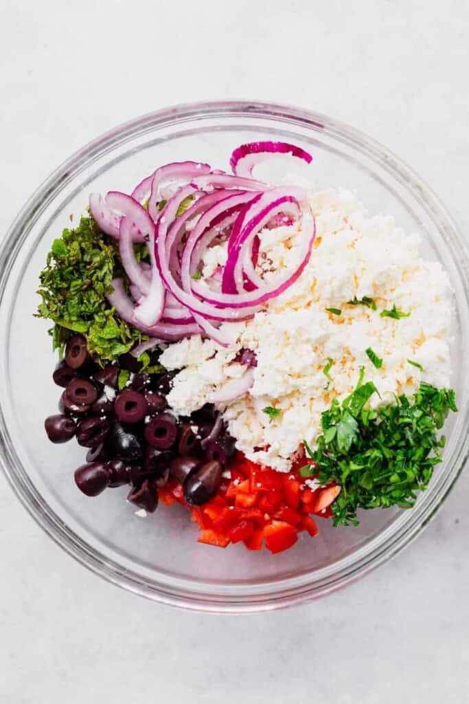 Olives, pepper, mint, parsley, feta, and onion in bowl.