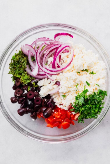 the ingredients for a greek salad in a bowl.