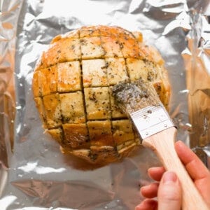 a person using a knife to cut a loaf of bread.