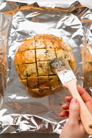 a person using a knife to cut a loaf of bread.