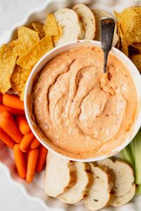 A slow cooker queso dip served with carrots and celery.