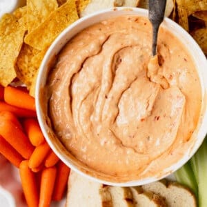 A slow cooker queso dip served with carrots and celery.