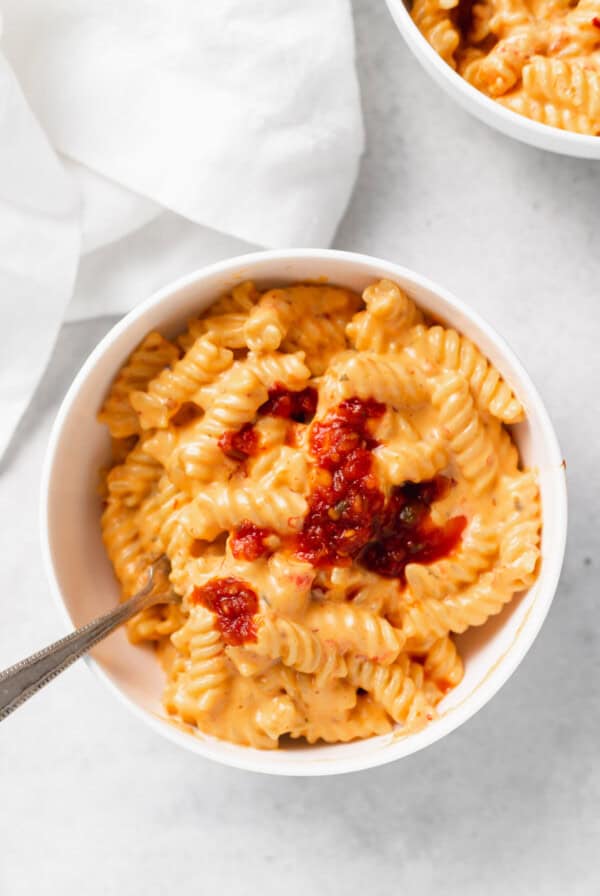 two bowls of pasta with sauce and a spoon.