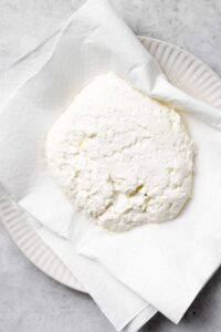 pressing ricotta cheese in paper towel.