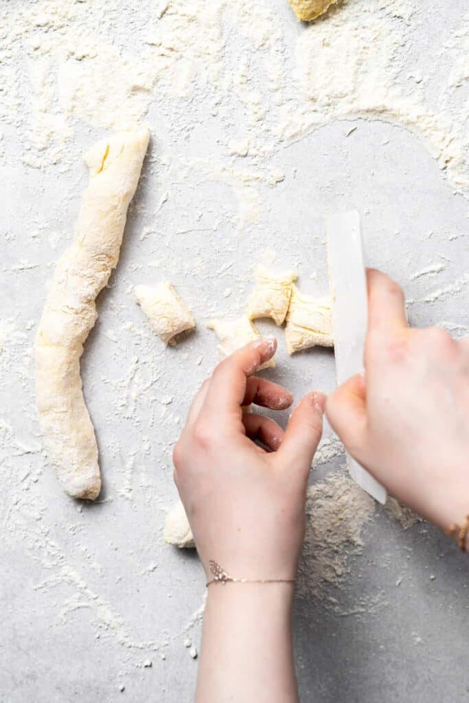 ricotta gnocchi dough being cut into bite-sized pieces