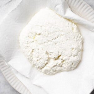 pressing ricotta cheese in paper towel.