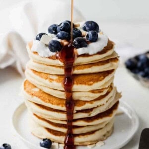 Ricotta pancakes stacked with blueberries and drizzled with syrup.