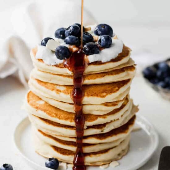 Ricotta pancakes stacked with blueberries and drizzled with syrup.