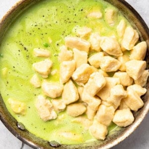 A frying pan with ricotta gnocchi and sweet pea butter sauce.