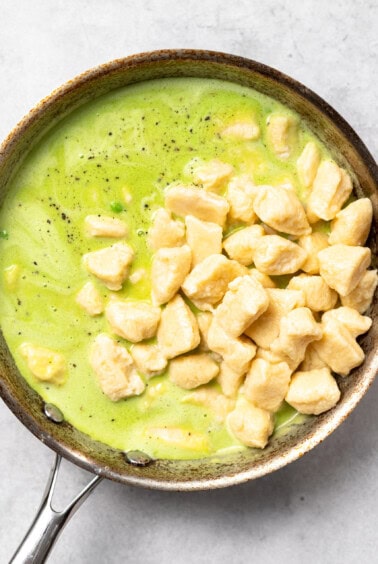 A frying pan with ricotta gnocchi and sweet pea butter sauce.