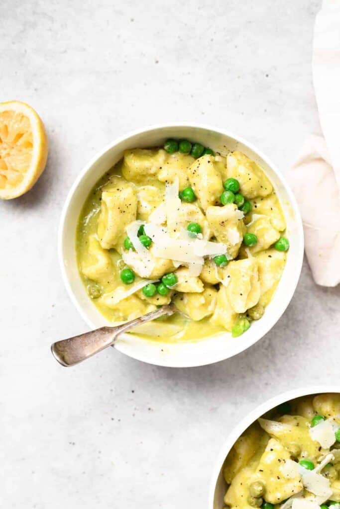 ricotta gnocchi with sweet pea butter sauce in a bowl topped with pecorino