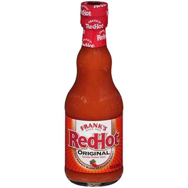 A bottle of red hot sauce placed on a white background, perfect for spicing up Buffalo Chicken Nachos.