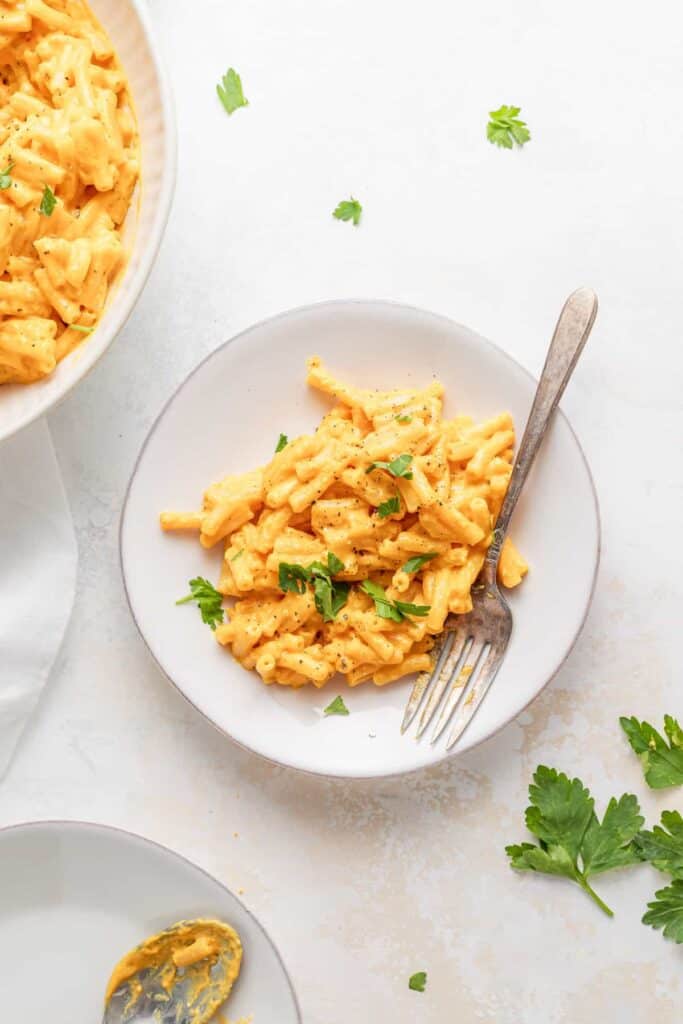 A bowl of mac and cheese with parsley on top. 