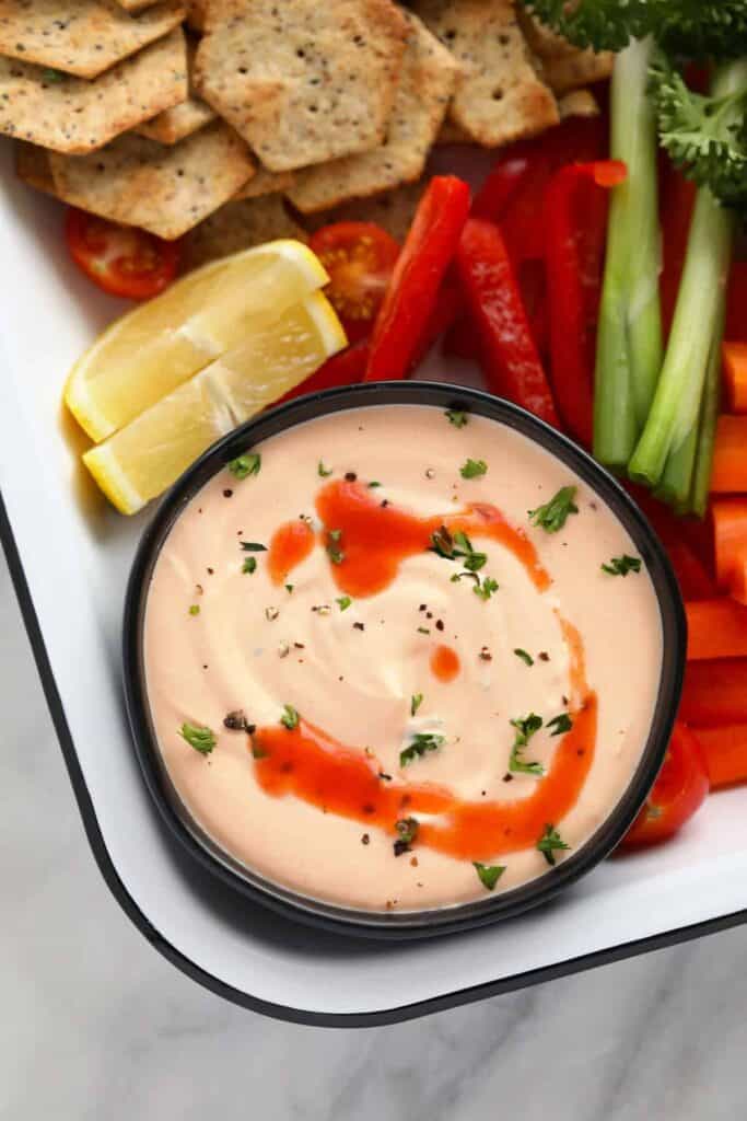 buffalo whipped cottage cheese dip in a bowl surrounded by veggies to dip into it