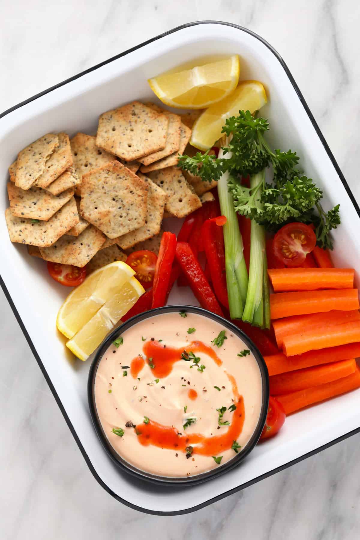 whipped cottage cheese dip in a bowl with veggies and crackers around it ready to be dipped in