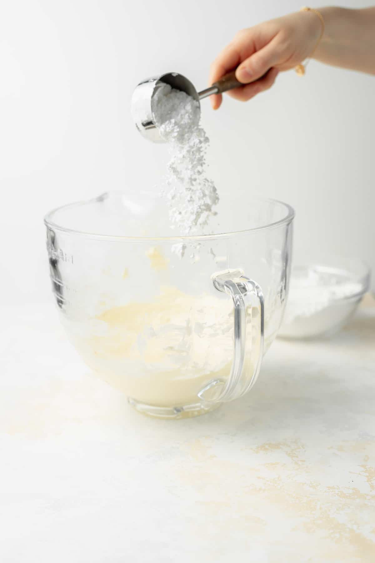 adding powdered sugar to glass bowl