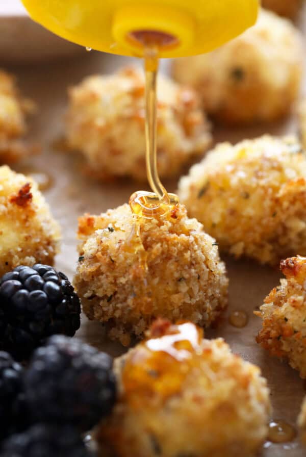 a spoon drizzling honey over a bunch of fruit.