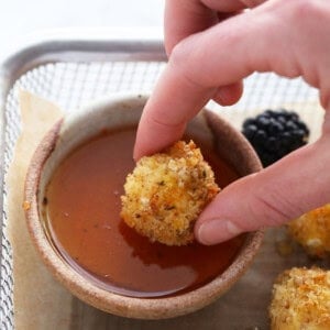 a person dipping some food into a bowl.