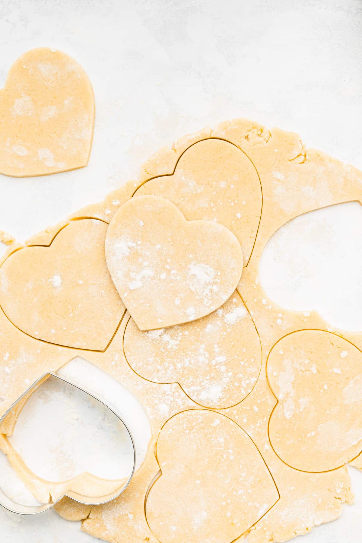 cream cheese heart cookie dough cut out into hearts with a cookie cutter