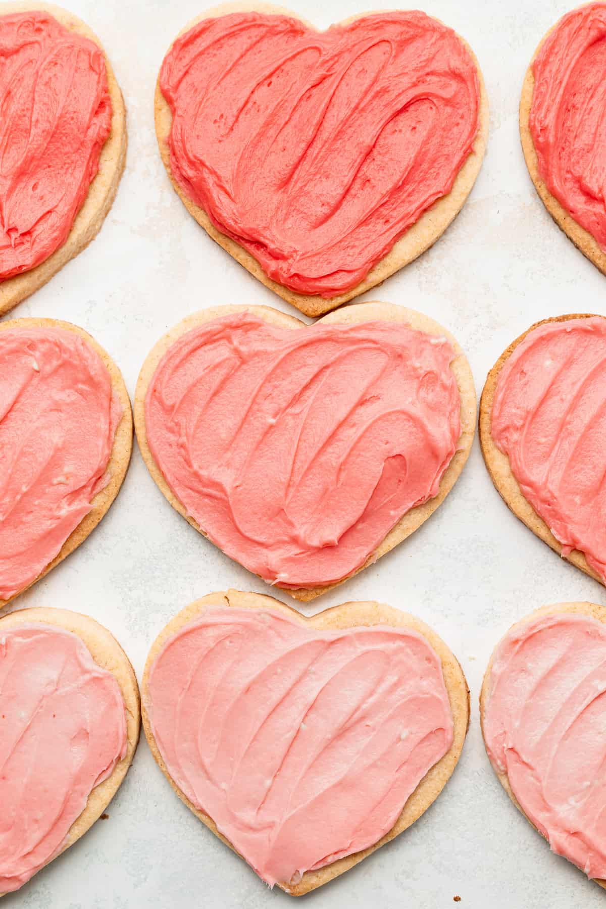 cream cheese heart cookies frosted with various shades of pink frosting