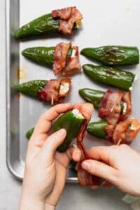 bacon wrapped jalapenos on a baking sheet.