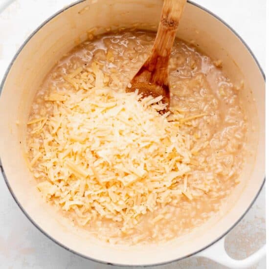 a pot of rice with cheese and a wooden spoon.