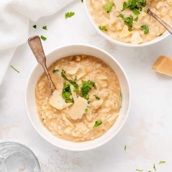 two bowls of risotto with parmesan cheese and parsley.