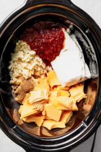 a crock pot filled with cheese and other ingredients.