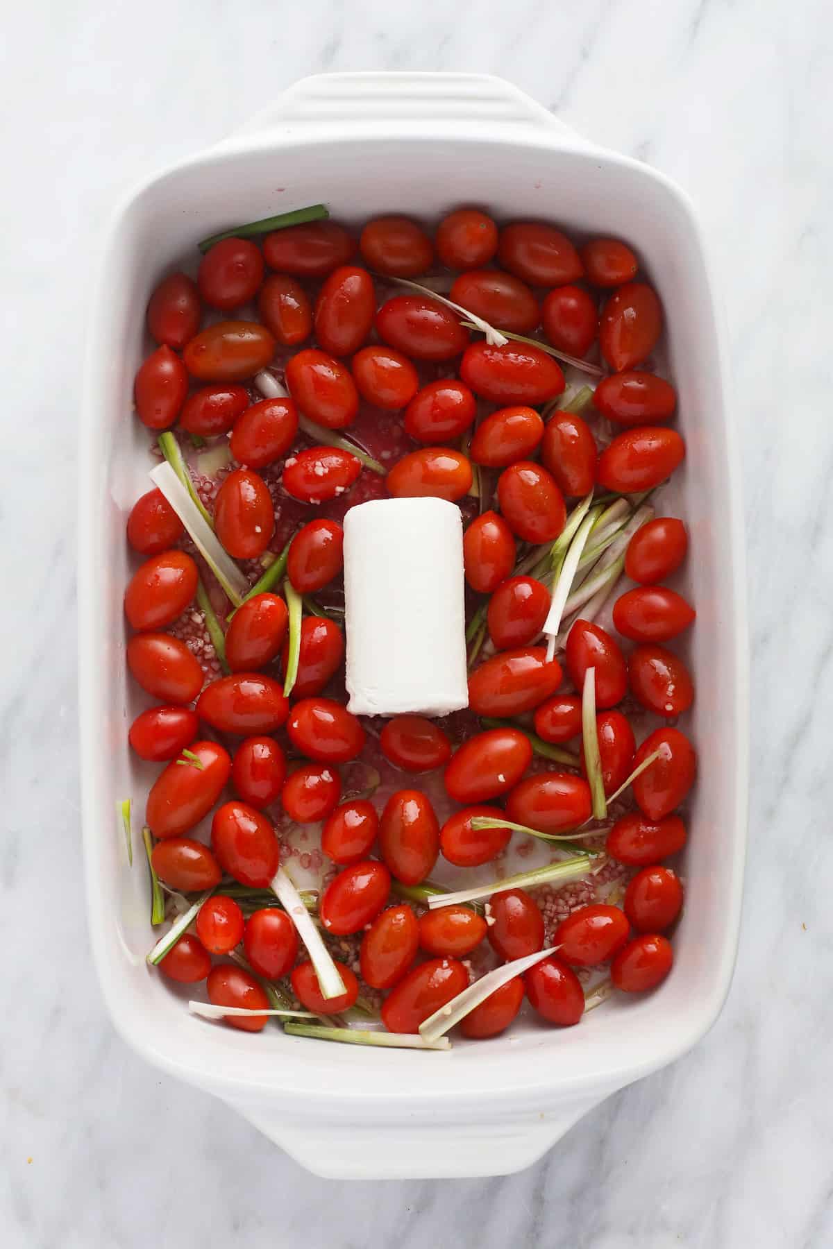 Goat cheese and tomatoes in a casserole dish. 