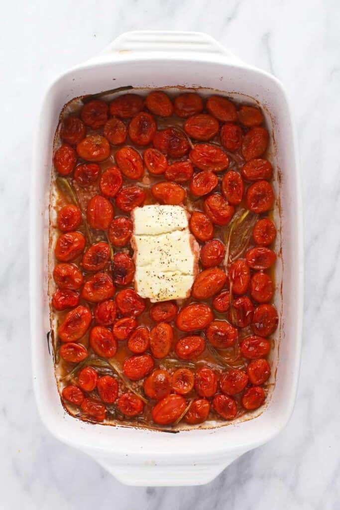 Goat cheese and tomatoes in casserole dish. 