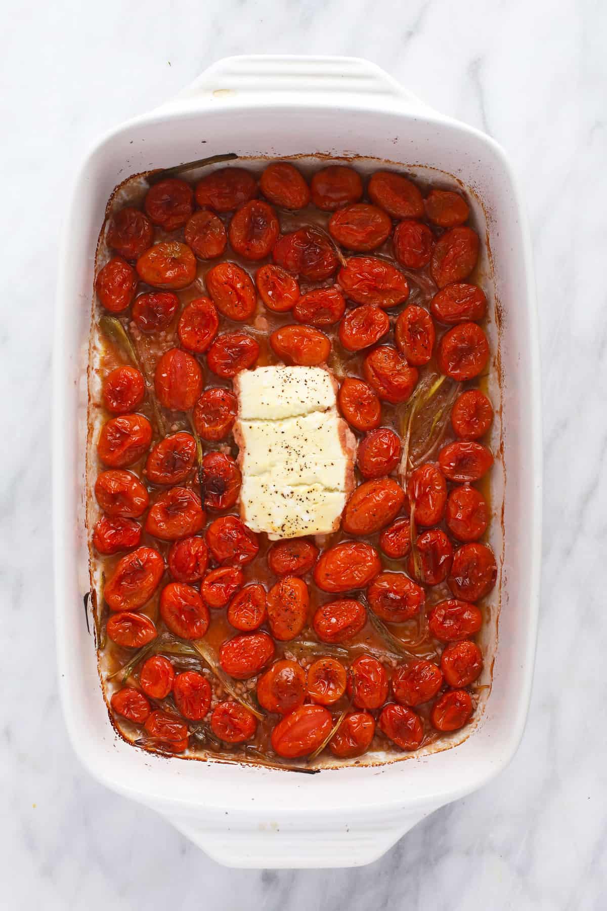 Goat cheese and tomatoes in casserole dish. 