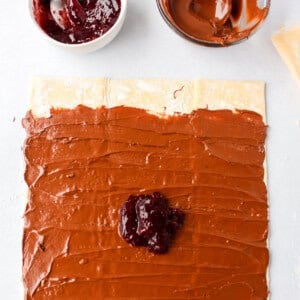 A chocolate pastry with raspberry jam and icing on it.