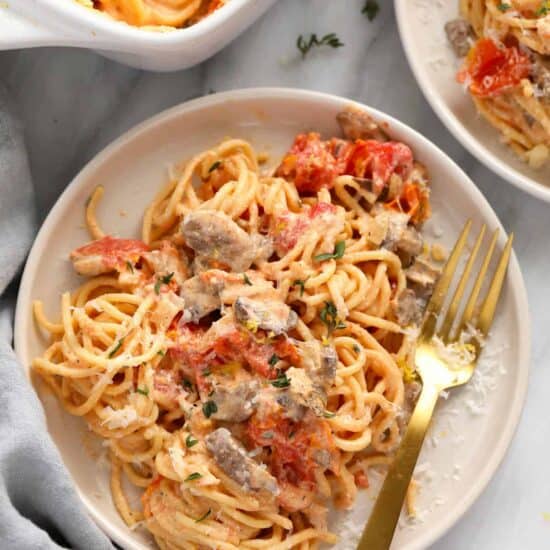 A plate of baked cream cheese pasta and meatballs with a fork.