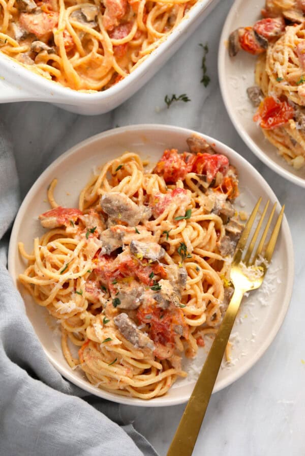 A plate of baked cream cheese pasta and meatballs with a fork.