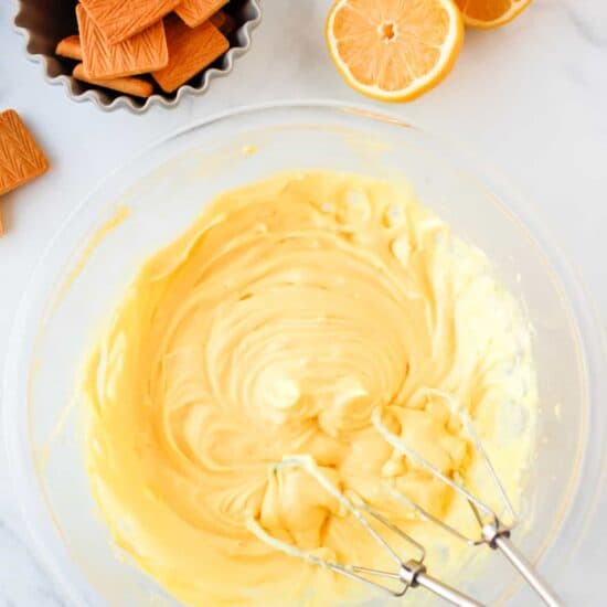 a bowl of whipped cream with oranges and crackers.