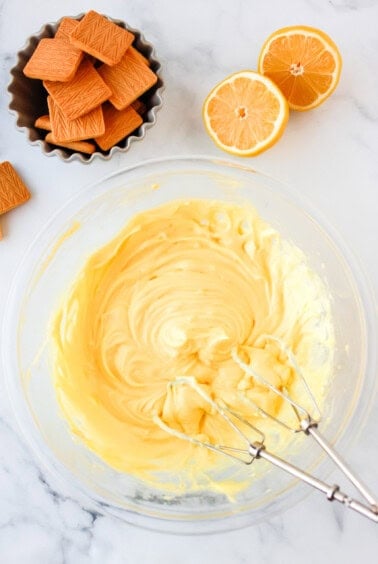 a bowl of whipped cream with oranges and crackers.