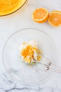 a glass bowl with orange slices and a fork.