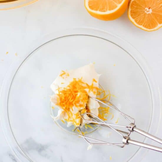 a glass bowl with orange slices and a fork.