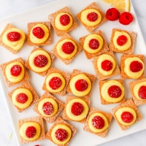 a plate with lemon and raspberry tarts on it.