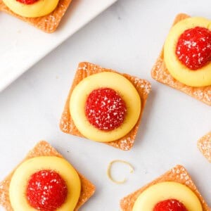 a white plate with lemon tarts and raspberries on it.